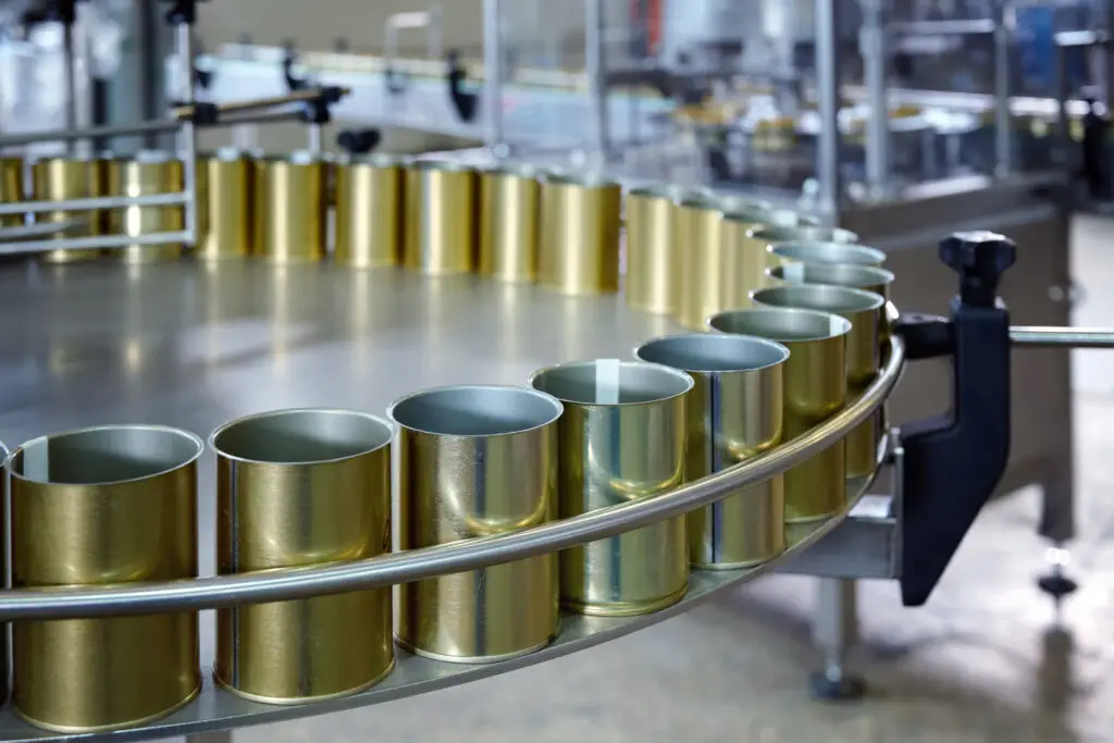 A close-up of empty cans moving along a canning conveyor belt.